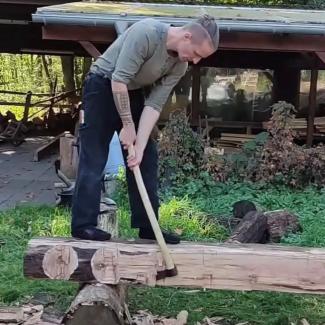 Photo showing Ludwig Steiger hewing a beam.